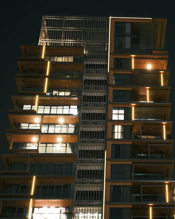 Fachada de edifício residencial contemporâneo à noite, com apartamentos iluminados