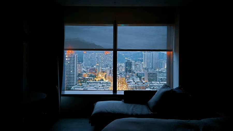Sala de apartamento com janela ampla para a cidade iluminada à noite
